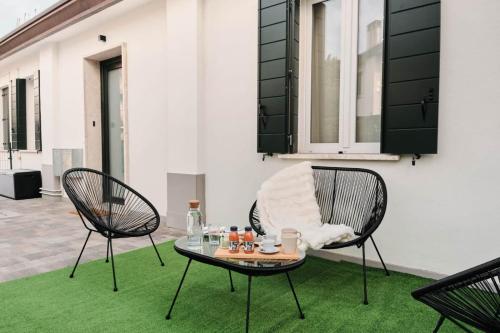 two chairs and a table on a green rug at Ortensie House in Padova