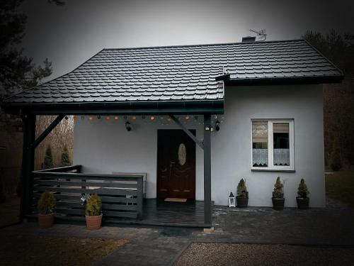 a small white house with a porch and a door at Lazurowy Zakątek in Życiny
