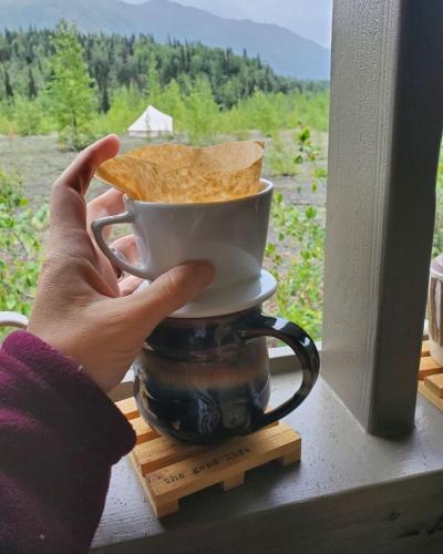 a person holding a cup with a piece of toast at Alaskan Glamping in Anchorage