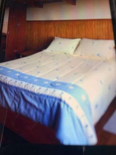 a large bed with blue and white sheets and pillows at Cabañas río seco in Punta Arenas