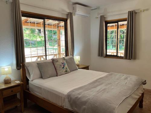 a bedroom with a large bed with two windows at Villa Maria Anse Corail in Takamaka