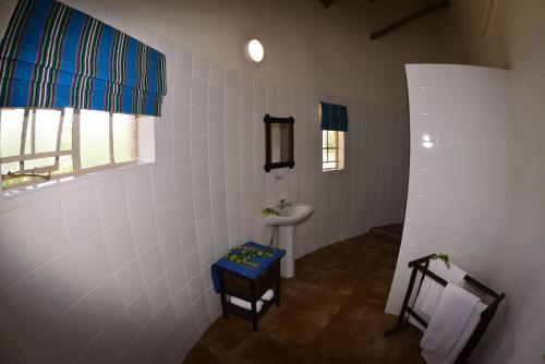La salle de bains blanche est pourvue d'un lavabo et de toilettes. dans l'établissement Awelani Lodge, à Masisi