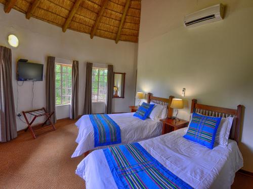 a bedroom with two beds and a flat screen tv at Awelani Lodge in Masisi