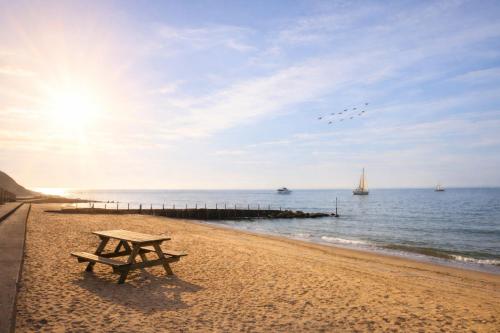 a picnic table on the beach near the water at Thurnefield Holiday Cottages in Potter Heigham