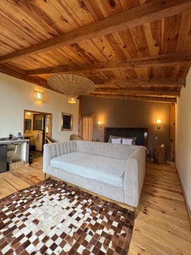 a large white couch in a living room with wooden ceilings at NIDU Cabañas Boutique & Holística in Mineral del Monte
