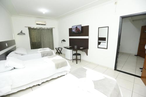 a white bedroom with a bed and a table at Eder Hotel in Cacoal