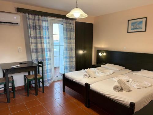a bedroom with two beds and a desk and a window at Bay Watch in Karpathos