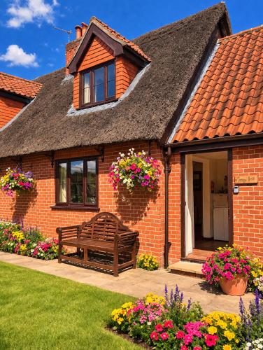 a brick house with a bench in the yard at Thurnefield Holiday Cottages in Potter Heigham