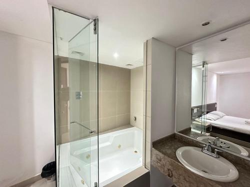 a bathroom with a glass shower and a sink at Hotel Via 45 Centro in Medellín