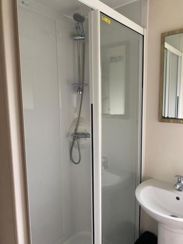 a shower with a glass door next to a sink at Caravan Holiday Park in Newquay in Newquay