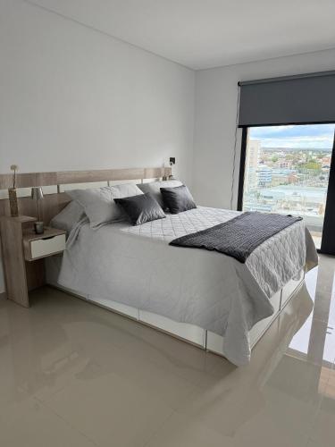 a white bedroom with a large bed and a window at Portal Patagónico in Puerto Madryn