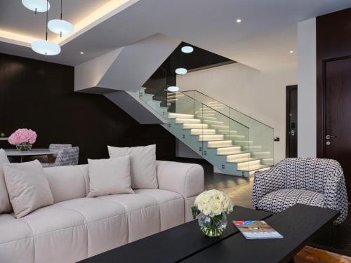 a living room with a white couch and a staircase at Qafqaz Riverside Hotel in Gabala