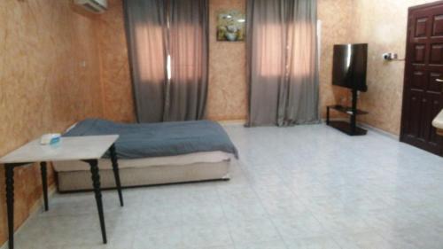 a bedroom with a bed and a table and a television at House Estrella - 11 in Al Ain