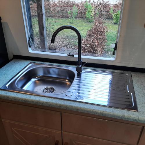 a sink in a kitchen with a window at Stacaravan in De Pol