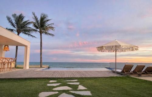 a patio with chairs and an umbrella and the ocean at Casa Praia Parati in Anchieta