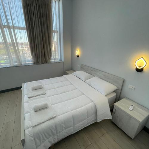 a bedroom with a large white bed with a large window at Hotel RADOJA in Shkodër