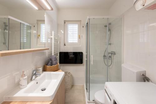 a white bathroom with a sink and a shower at SeaView Lovran in Lovran