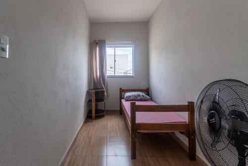 a room with a bed and a fan and a window at Apartamento 4 quartos com Wi Fi e Garagem in Pará de Minas