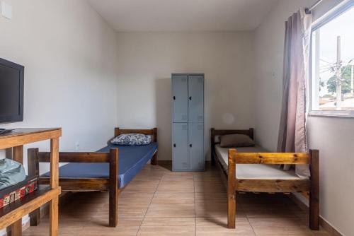 a room with two beds and a cabinet and a tv at Apartamento 4 quartos com Wi Fi e Garagem in Pará de Minas