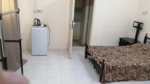 a room with two beds and a small refrigerator at House Sol - 8 in Al Ain