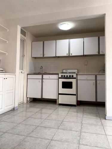 an empty kitchen with a stove and white cabinets at Cozy house in the Angelópolis area in La Concepción