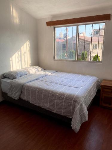 a bedroom with a bed with a blue blanket and a window at Cozy house in the Angelópolis area in La Concepción