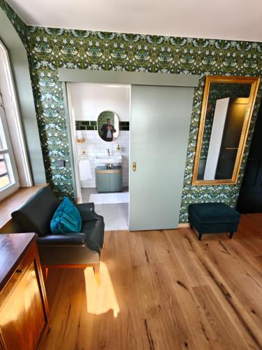 a living room with a black couch and a mirror at 3sine - Ihr besonderer Gasthof im Bahnhof Deisenhofen in Oberhaching