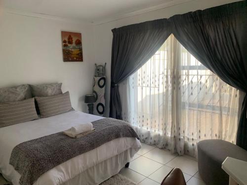 a bedroom with a bed and a large window at Cottage @19th in Pretoria