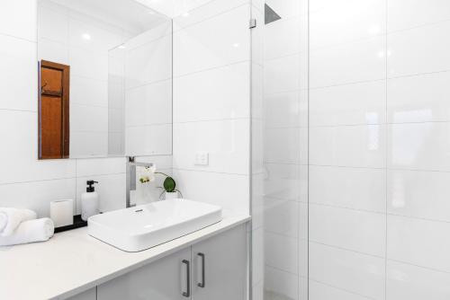 a white bathroom with a sink and a mirror at North Perth 3BR Home Steps To Hyde Park & Dining in Perth