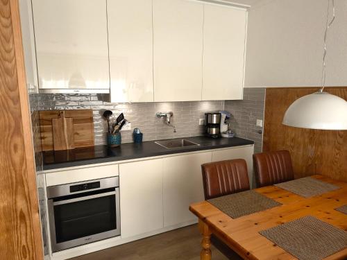 a kitchen with white cabinets and a wooden table at ZEEWIND Bed by the Sea in Westkapelle