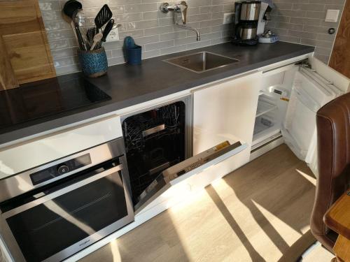 a kitchen with an open dishwasher and a sink at ZEEWIND Bed by the Sea in Westkapelle