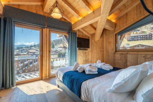 a bedroom with a bed and a large window at Chalet Téléporté Jacuzzi Hammam Cheminée 14 pers - MultiPass in Les Gets