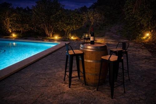 a bottle of wine sitting on a barrel next to a pool at Villa Es Puig, piscina y vistas a la montaña in Santa Margalida