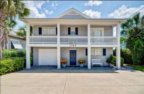 a large white house with a bench in front of it at Dog Friendly Ground Level Duplex in Fernandina Beach
