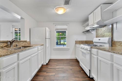 a kitchen with white cabinets and a white refrigerator at The Downtown Cedar in Ocean Springs