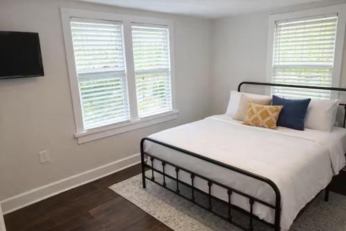 a white bedroom with a bed with pillows and windows at The Downtown Cedar in Ocean Springs