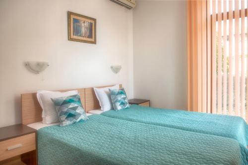 a bedroom with two beds with blue sheets and a window at Montemar Villas in Sunny Beach