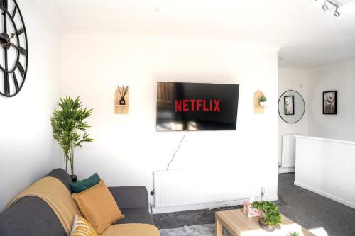 a living room with a couch and a tv on the wall at Modern Luxurious Apartment with Balcony in Shenley Church End