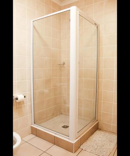 a shower with a glass door in a bathroom at Cozy guestrooms in Midrand in Midrand
