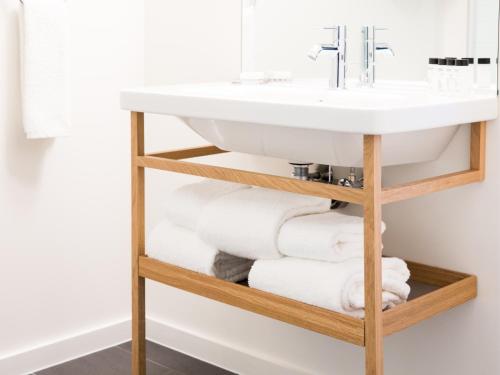 a bathroom with a sink and a pile of towels at The Study at University City in Philadelphia