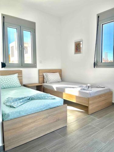 two beds in a room with two windows at Nóstos Home in Kos
