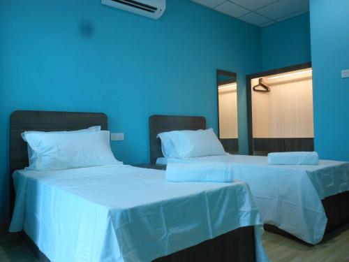 two beds in a room with blue walls at Eiman Homestay, Kluang in Kluang