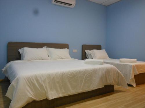 two beds in a room with blue walls at Eiman Homestay, Kluang in Kluang