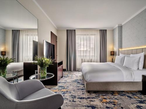 a hotel room with a large bed and a chair at Crowne Plaza Bratislava by IHG in Bratislava