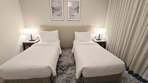 two beds in a hotel room with two lamps at Three Bedrooms Apartment at Address Residence Fujairah by Solo Realty in Fujairah