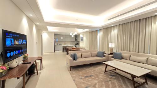 a living room with a couch and a tv at Three Bedrooms Apartment at Address Residence Fujairah by Solo Realty in Fujairah