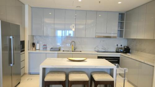 a white kitchen with a table and stools in it at Three Bedrooms Apartment at Address Residence Fujairah by Solo Realty in Fujairah