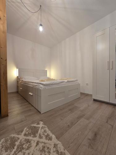 a white bedroom with a bed and a rug at Merci Apartament 2,0 in Sibiu