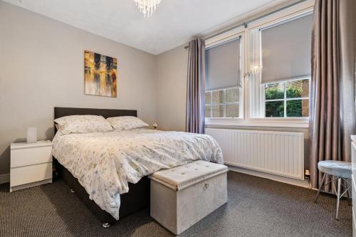 a bedroom with a bed and two windows at Mar Apartment in Stirling