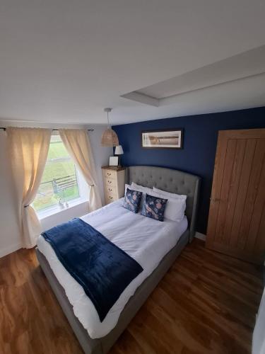 a bedroom with a bed with blue walls and a window at Lancaster Cottage in Hawes